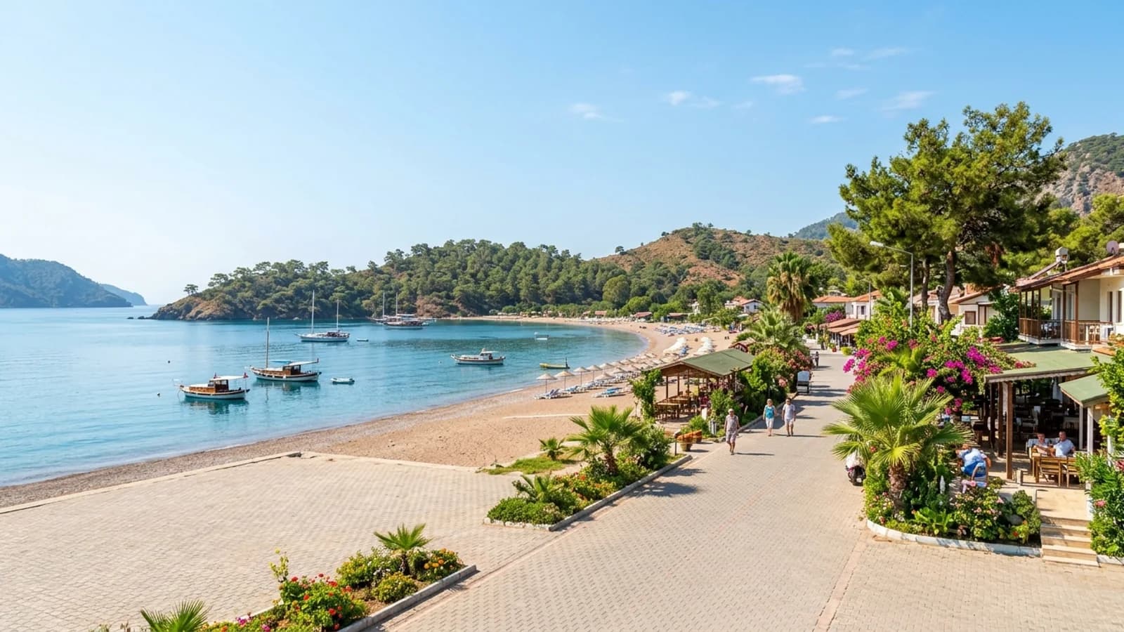 Baie tranquille et plage d'Adrasan La baie paisible d'Adrasan avec une plage calme, des caps boisés et des bateaux sur l'eau limpide.