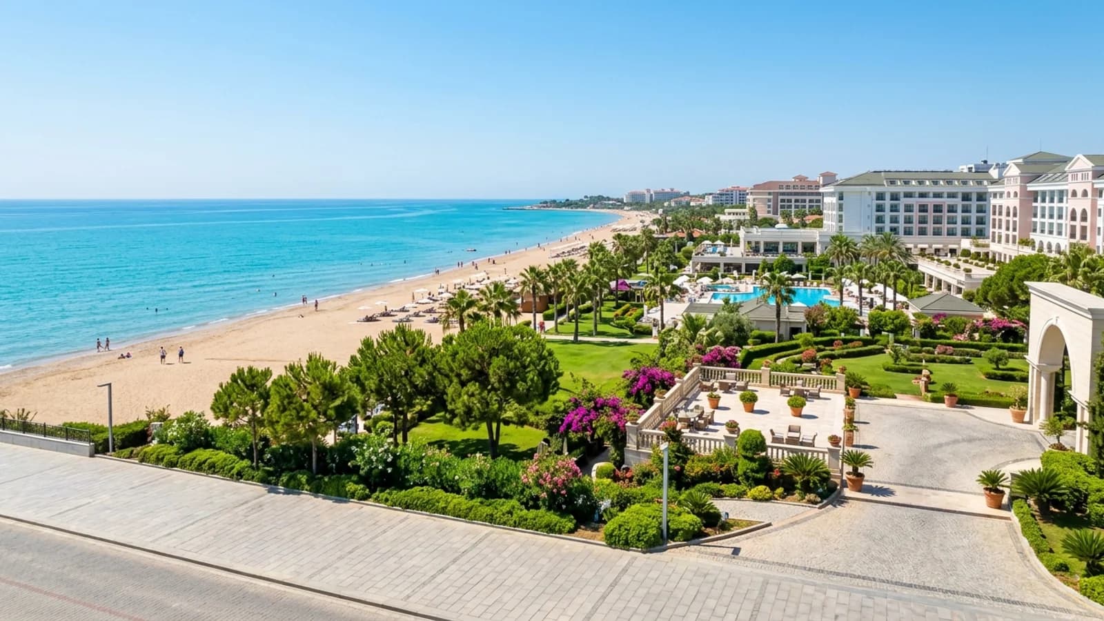 Plage de sable et hôtels à Gündoğdu Plage de sable à Gündoğdu avec de grands hôtels, des pelouses vertes et une mer calme.