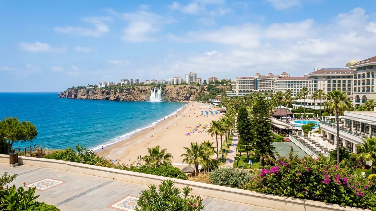 Lara-Strand und Wasserfall bei Antalya Der sandige Lara-Strand mit Resort-Hotels und einem weißen Wasserfall, der von Klippen ins blaue Meer stürzt.