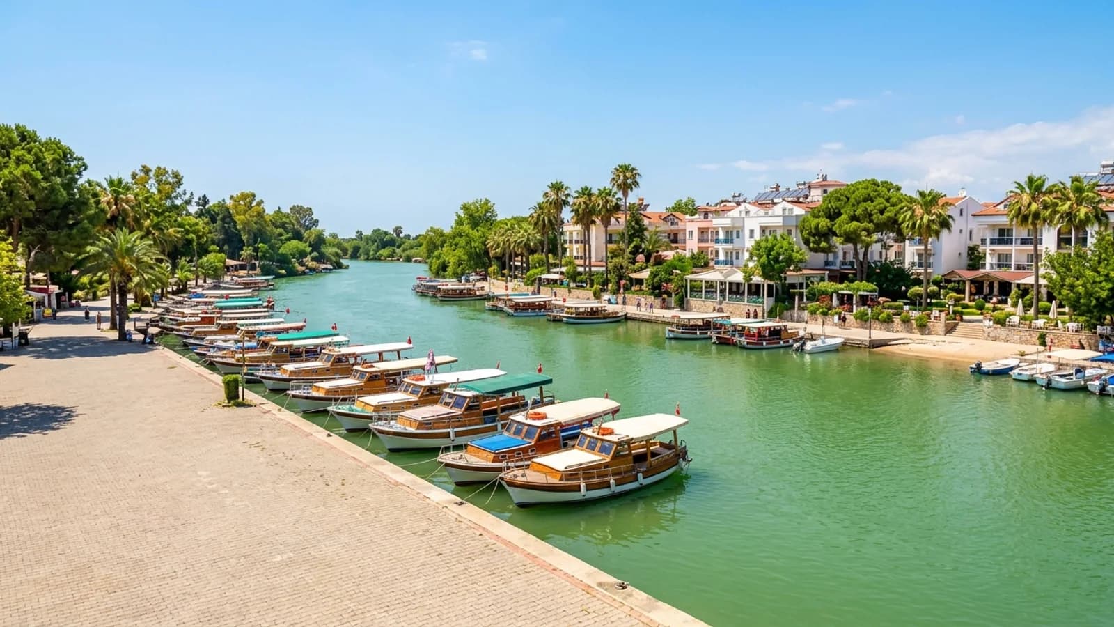 Houten boten op de rivier Manavgat Kleurrijke houten boten liggen aangemeerd langs de oevers van de brede groene rivier de Manavgat.