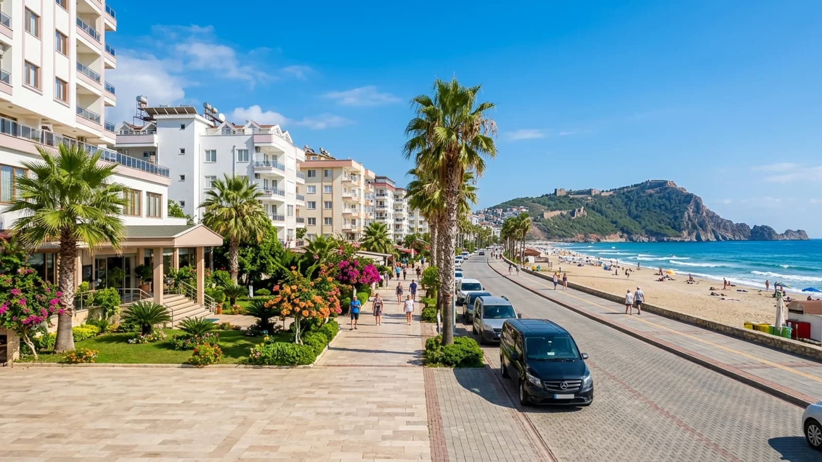 Strandpromenade im Urlaubsort Oba bei Alanya Eine von Palmen gesäumte Strandpromenade in Oba, Alanya, mit der Burghalbinsel im Hintergrund.